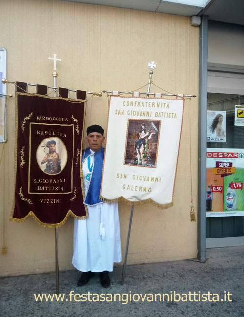 27/08/2017. Il confrate Pippo Di Mariano tra lo stendardo della confraternita di San Giovanni Battista di Vizzini (a sinistra) e lo stendardo della confraternita di San Gio.Battista di S.G. Galermo (a destra).